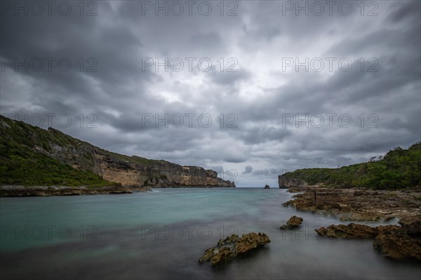 Rocky coast, long bay by the sea at sunset. Dangerous view of the Caribbean Sea. Tropical climate on a cloudy day in La Porte d'Enfer, Grande Terre, Guadeloupe, French Antilles, North America