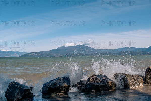 Splashing waves hitting rocks on the shore of Lake Garda, Sirmione, Lake Garda, Italy, Europe