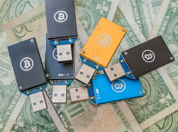 Various USB hardware wallets with Bitcoin logos on them, displayed on US dollar bills, in South Korea