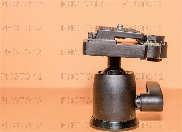 Closeup side view of quick release tripod head on brown background