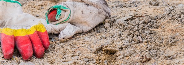 Worn work gloves discarded among construction debris and dirt, in South Korea