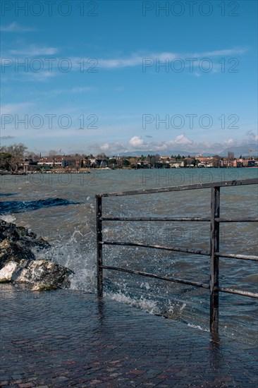 Splashing waves hitting rocks on the shore of Lake Garda, Sirmione, Lake Garda, Italy, Europe