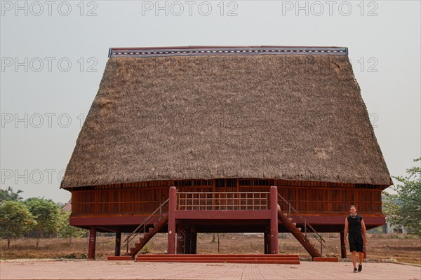 A tourist exploring a traditional architecture of a Bahnar ethnic stilt house or Rong House in Pleiku countryside, Vietnam, Asia