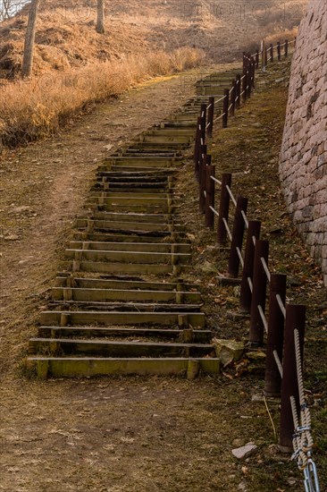 Wooden stairs on mountainside beside section of mountain fortress wall made of flat stones located in Boeun, South Korea, Asia