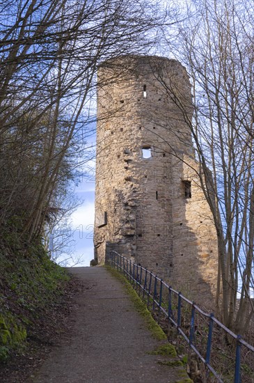 Steep path with blue railings from the castle hotel up to the ruins of Volmarstein Castle, remains of a tower on the right, branches and green vegetation on the slope to the left, Volmarstein, Ruhgebiet, Germany, Europe