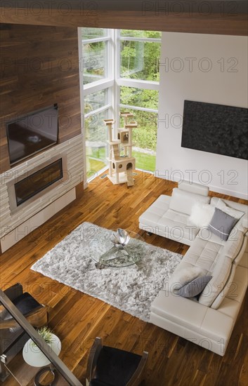 High angle view of living room with creamy beige colored L-shaped leather sofa and gas fireplace inside luxurious home, Quebec, Canada, North America