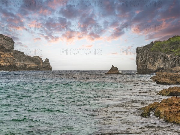 Rocky coast, long bay by the sea at sunset. Dangerous view of the Caribbean Sea. Tropical climate at sunset in La Porte d'Enfer, Grande Terre, Guadeloupe, French Antilles, North America