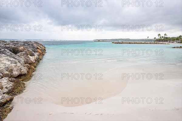 Caribbean dream beach with palm trees, white sandy beach and turquoise-coloured, crystal-clear water in the sea. Shallow bay on a cloudy day. Plage de Sainte Anne, Grande Terre, Guadeloupe, French Antilles, North America