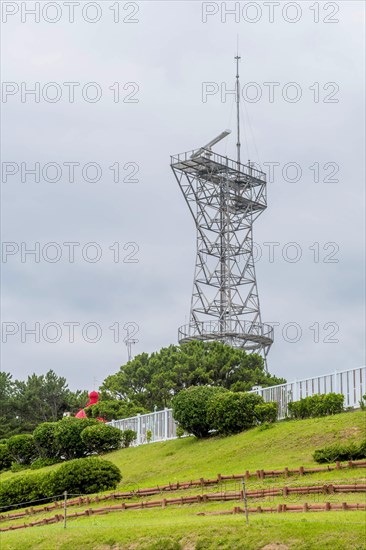 Tall metal radar tower standing amidst lush greenery under a cloudy sky, in Ulsan, South Korea, Asia