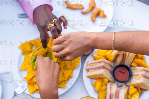 Top view of friends dipping nachos in the sauce enjoying together in a restaurant