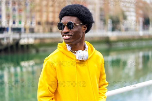 Stylish african man with sunglasses standing outdoors next to a urban river