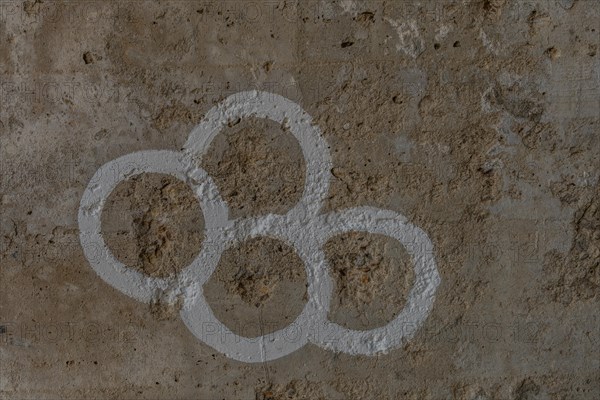 Simple graffiti of three interlinked rings on a rough concrete wall, in South Korea
