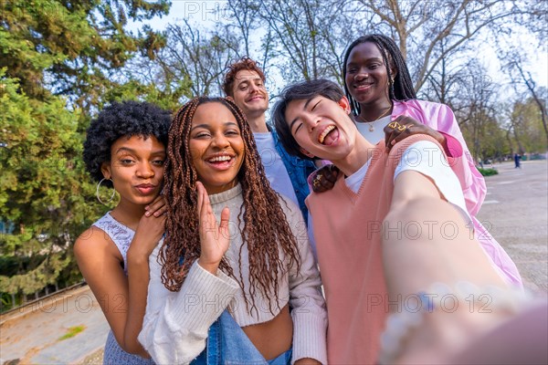 Japanese young man taking selfie with multi-ethnic friends standing together in an urban park