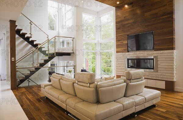 Living room with creamy beige colored L-shaped leather sofa and gas fireplace inside luxurious home, Quebec, Canada, North America