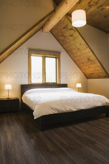 King size bed in master bedroom on upstairs floor inside contemporary style log home, Quebec, Canada, North America