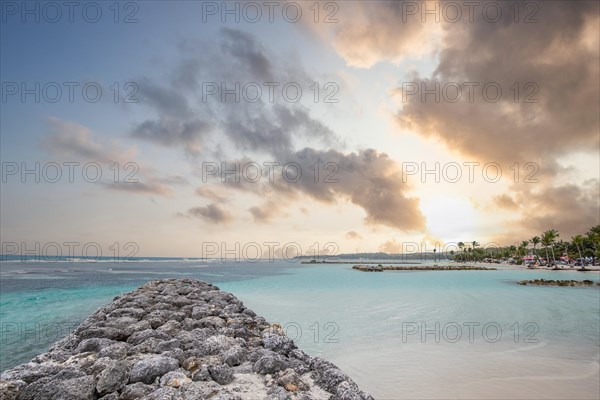 Caribbean dream beach with palm trees, white sandy beach and turquoise-coloured, crystal-clear water in the sea. Shallow bay at sunset. Plage de Sainte Anne, Grande Terre, Guadeloupe, French Antilles, North America