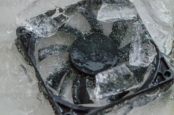 Closeup of computer case fan frozen in block of ice. Concept keep your computer cool