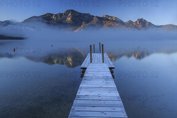 Morning atmosphere at mountain lake in front of mountains, footbridge, autumn, frost, fog, reflection, Lake Kochel, view of Herzogstand and Heimgarten, Alpine foothills, Bavaria, Germany, Europe