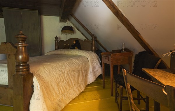 Antique wooden four-poster single bed and armoire in bedroom on upstairs floor inside old 1785 home, Quebec, Canada, North America