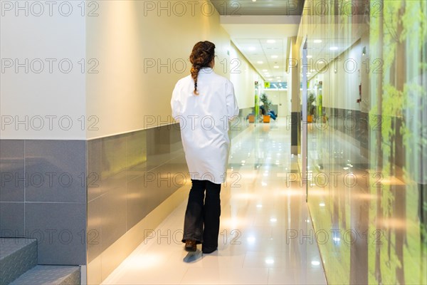 Rear view of a female ophthalmologist walking along a corridor in the clinic