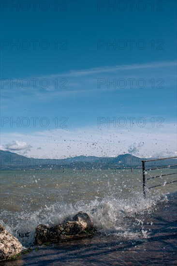 Splashing waves hitting rocks on the shore of Lake Garda, Sirmione, Lake Garda, Italy, Europe