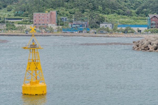 A yellow navigation buoy bobs in the ocean under a cloudy sky, marking safe passage, in Ulsan, South Korea, Asia