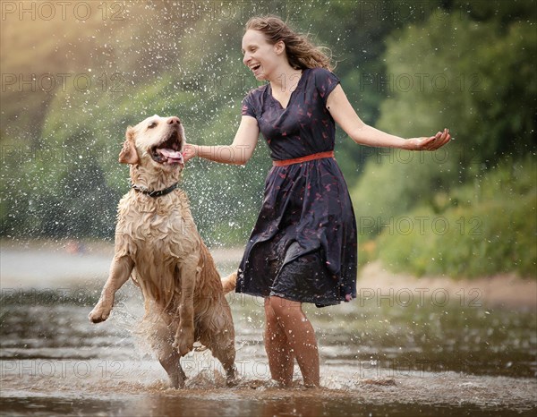 Labrador dog dirty muddy wet, shaking next to a woman in a dark summer dress, AI generated, AI generated