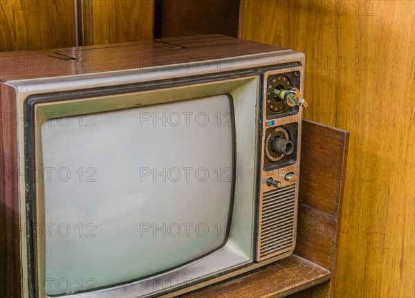 Old nineteen inch television set with wood grain chassis sitting on wooden desk. Located in an old naval vessal on display in public park in Gangneung, South Korea, Asia