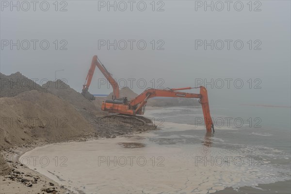 A foggy scene with an orange excavator by the water, in Ulsan, South Korea, Asia