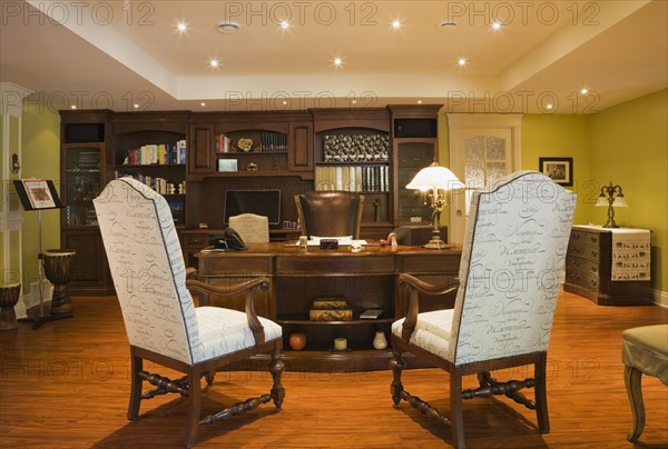 Wooden desk, high back chairs and wall unit in basement home office inside elegant style home, Quebec, Canada, North America