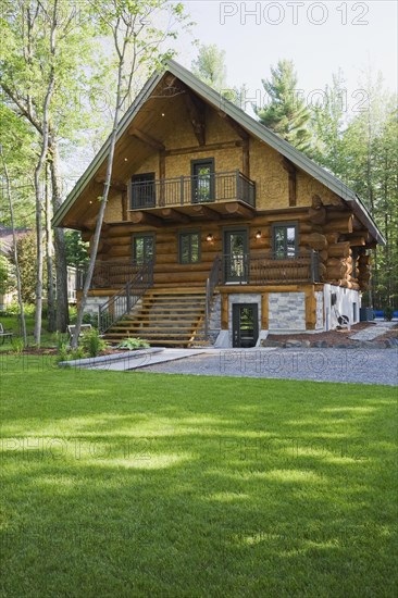 Luxurious two story Scandinavian style log cabin home facade in late spring, Quebec, Canada, North America
