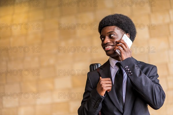 Low angle view portrait with copy space of a smiling african architect talking to the mobile phone in the city