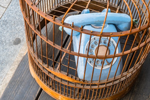 Old style rotary phone sitting in birdcage sitting outside on wooden step in Seoul, South Korea, Asia