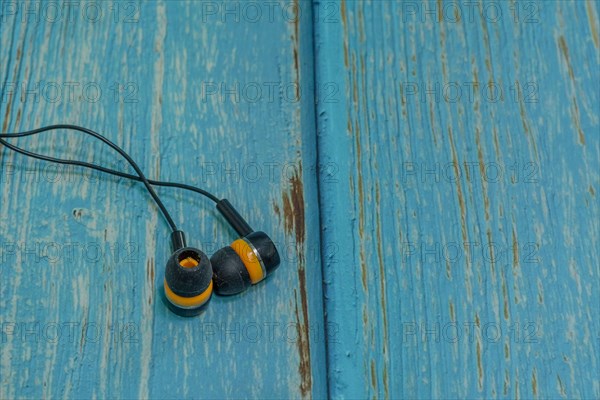 Set of black and yellow used ear buds on blue wood grain background