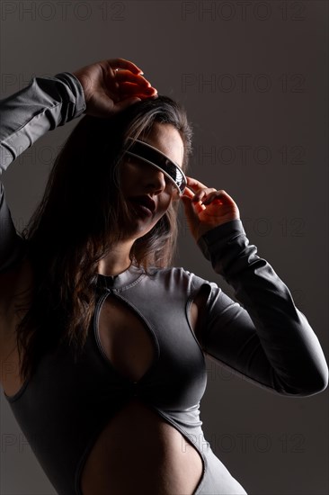 Studio portrait with grey background of a sensual woman using futuristic intelligent goggles