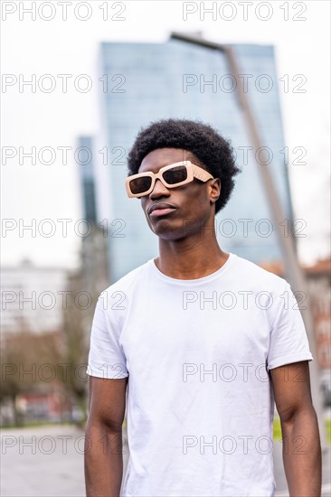 Vertical portrait of a modern african young man in sunglasses and casual clothes int he city