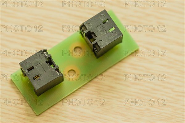 Two black plastic electrical connectors on a green circuit board, in South Korea