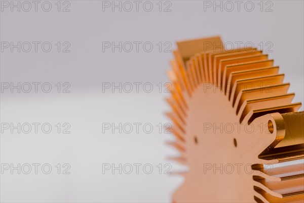 Closeup of fins and mounting flange on round copper computer heat sink on white background