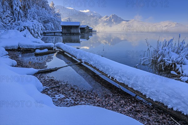 Morning atmosphere at mountain lake in front of mountains, boat huts, shore, winter, snow, reflection, Lake Kochel, Alpine foothills, Bavaria, Germany, Europe