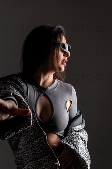 Studio portrait with grey background of a cool futuristic woman using intelligent goggles wearing elegant clothes