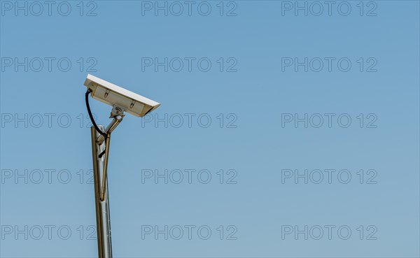 CCTV camera on shinny chrome plated pole against clear blue sky in South Korea