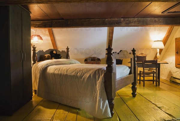 Antique wooden four-poster single bed and armoire in bedroom on upstairs floor inside old 1785 home, Quebec, Canada, North America
