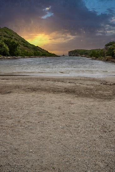 Rocky coast, long bay by the sea at sunset. Dangerous view of the Caribbean Sea. Tropical climate at sunset in La Porte d'Enfer, Grande Terre, Guadeloupe, French Antilles, North America