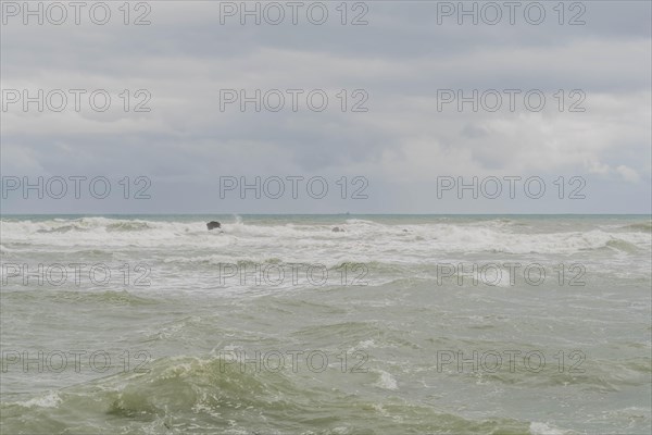 Choppy ocean waves under a cloudy sky with a solitary rock visible, in Ulsan, South Korea, Asia