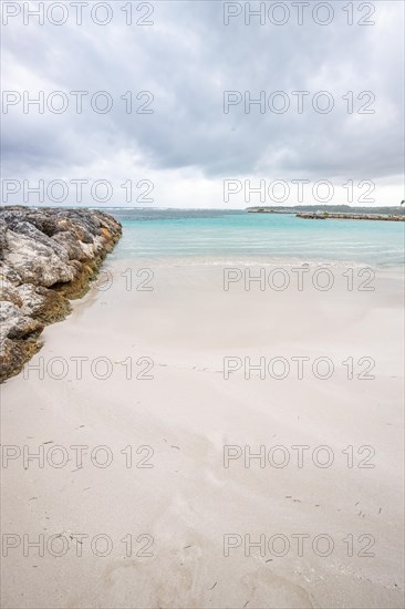 Caribbean dream beach with palm trees, white sandy beach and turquoise-coloured, crystal-clear water in the sea. Shallow bay on a cloudy day. Plage de Sainte Anne, Grande Terre, Guadeloupe, French Antilles, North America