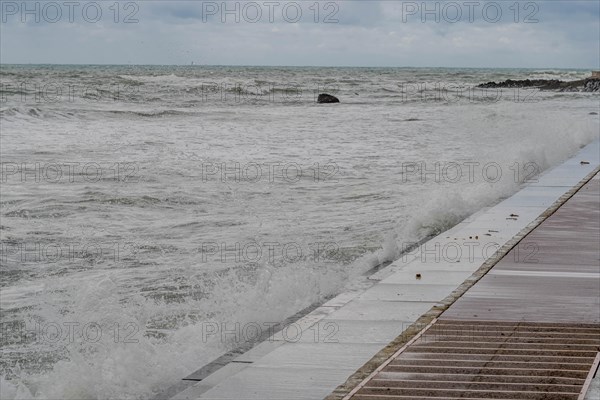 Waves crash against a sea wall creating whitecaps under an overcast sky, in Ulsan, South Korea, Asia