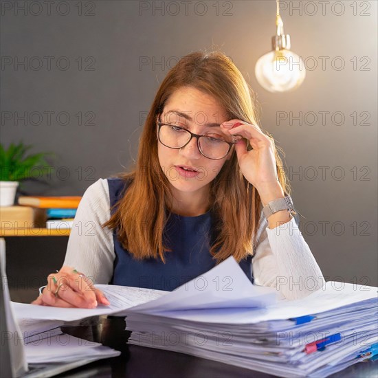 Woman concentrated reading documents at a desk in an office, symbol bureaucracy, AI generated, AI generated