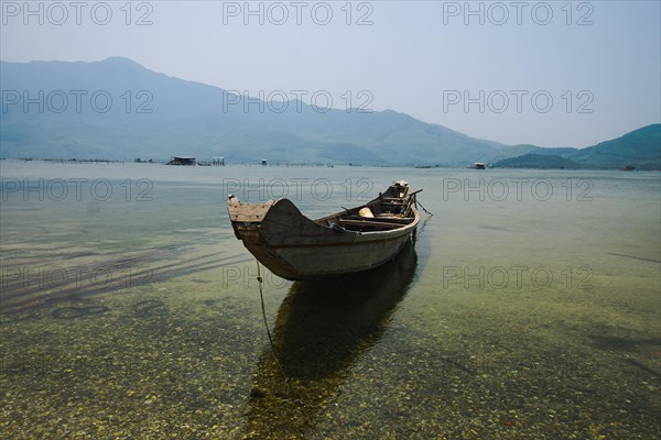 A solitary boat on still water with a clear mountain view, reflecting serenity and tranquility. Vietnam