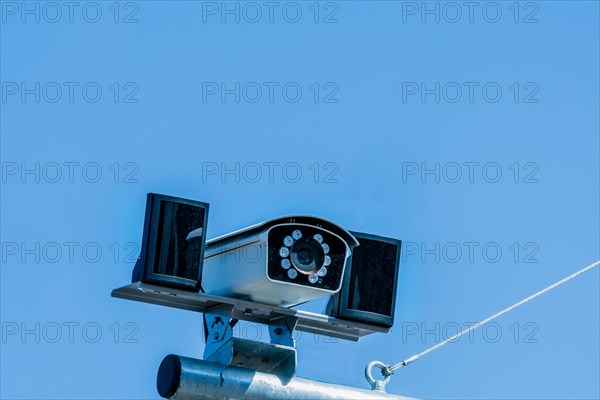 Closeup of closed circuit camera mounted on metal pole against light blue sky in background in South Korea