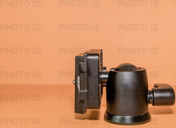 Closeup side view of quick release tripod head on brown background